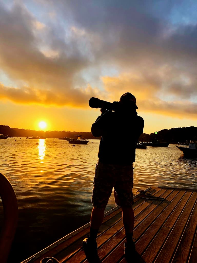Andrew photographing on a dock at sunset